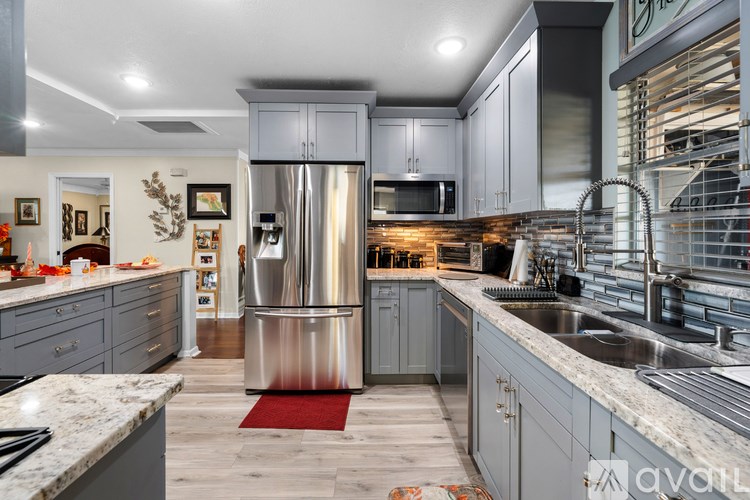 A modern kitchen with a stainless steel refrigerator and a marble countertop.