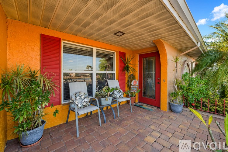A patio with a red door, two chairs and a table.