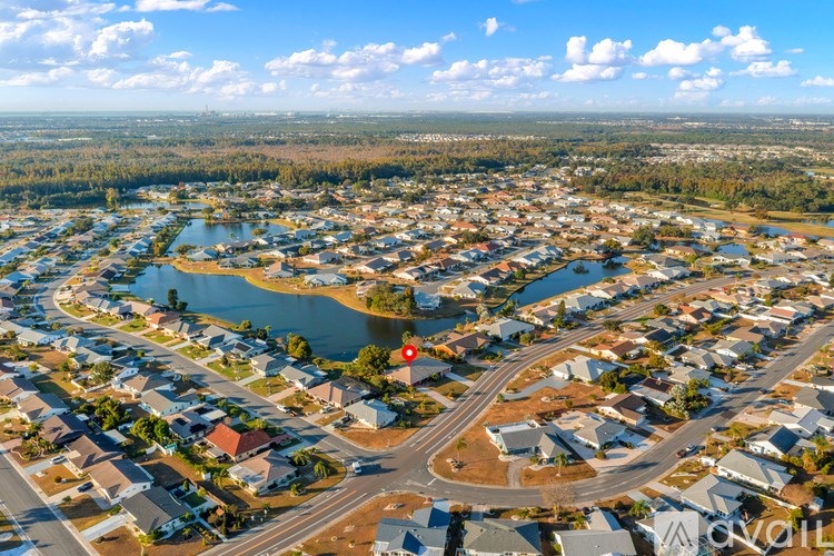 A bird's eye view of a residential area with a lake and a roundabout.