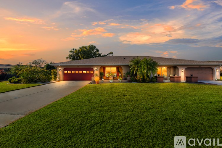 A house with a large lawn and a sunset in the background.