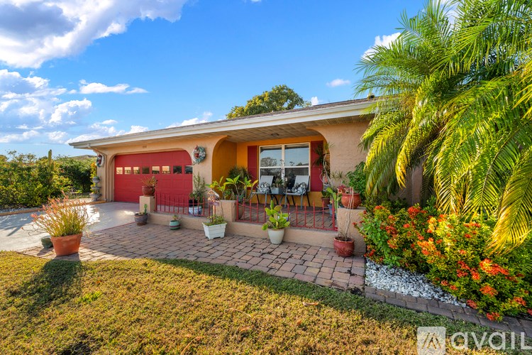 A house with a red garage door and a patio with chairs and plants.