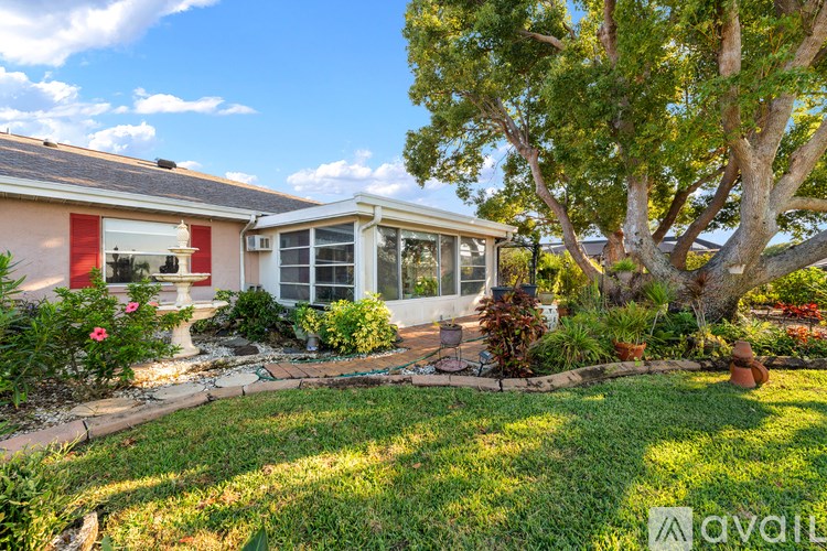 A house with a red awning and a tree in front.