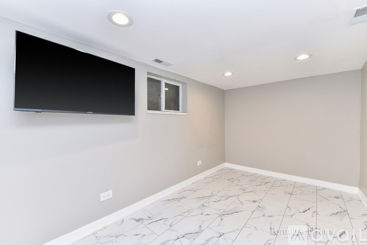 A room with a flat screen TV mounted on the wall and a window.