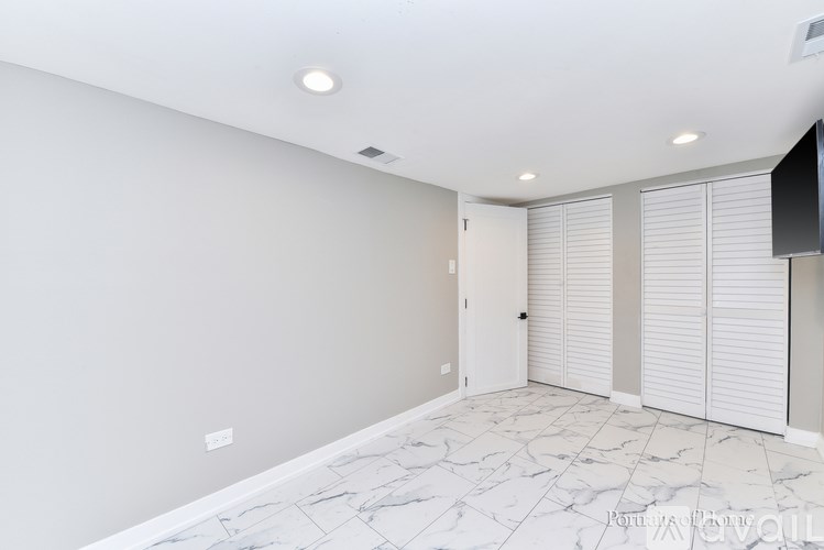 A spacious room with a marble floor and white walls.