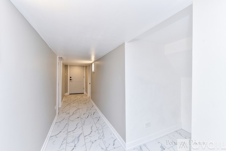 A hallway with marble flooring and white walls.