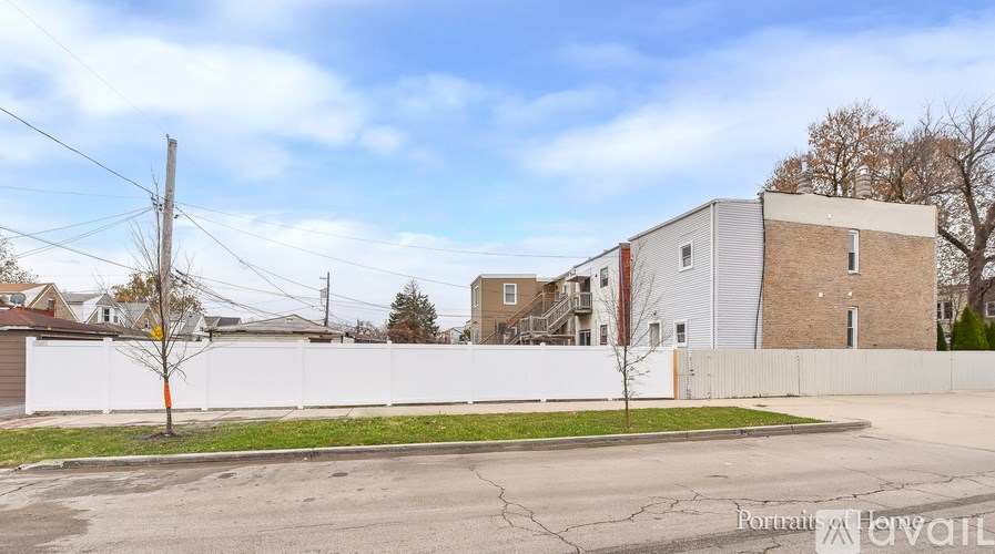 A street view with a white fence and a building in the background.