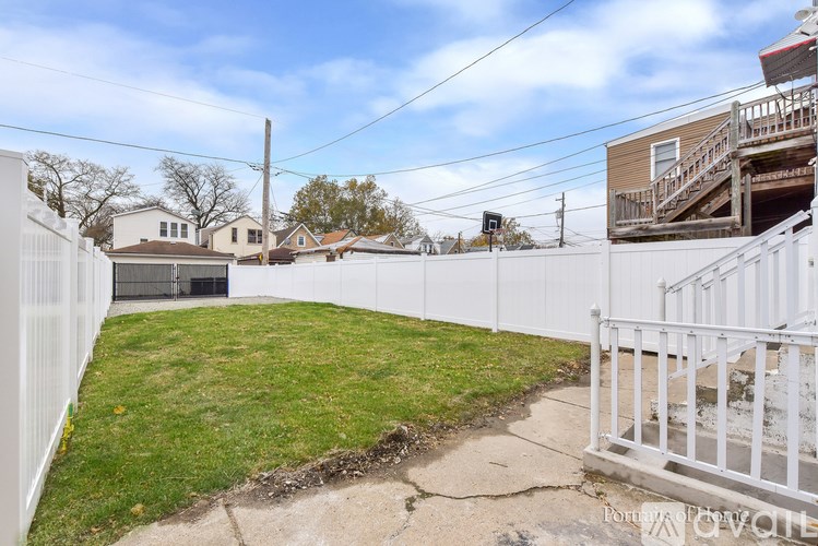 A backyard with a white fence and a grassy area.