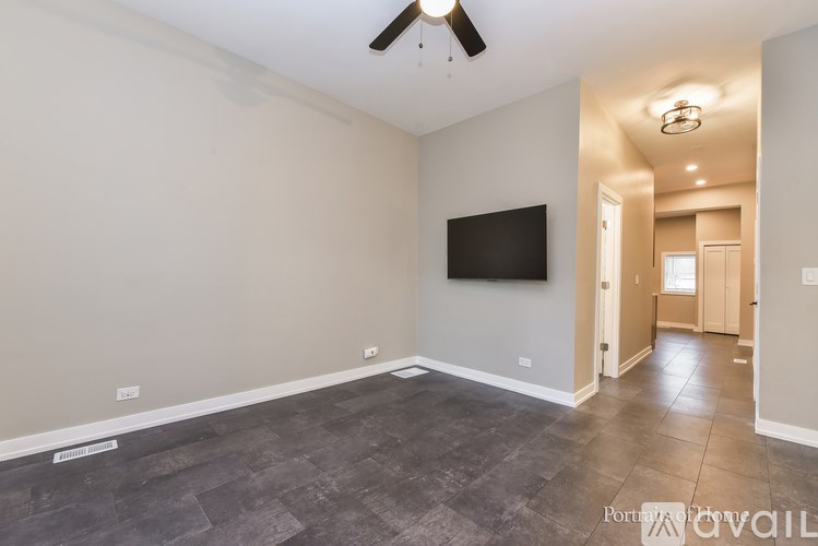 A spacious room with a ceiling fan and a flat-screen TV mounted on the wall.