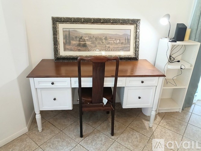 A brown chair sits in front of a white desk with a picture frame on top of it.