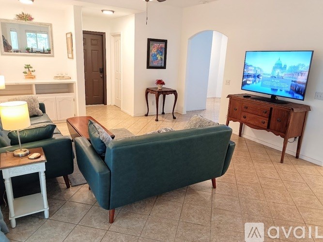 A living room with a green couch, a wooden side table, and a television.