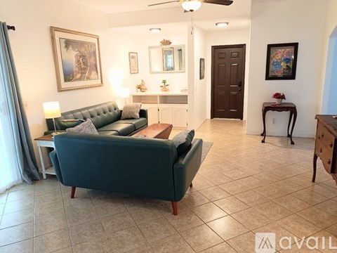 A living room with a green couch and a painting on the wall.