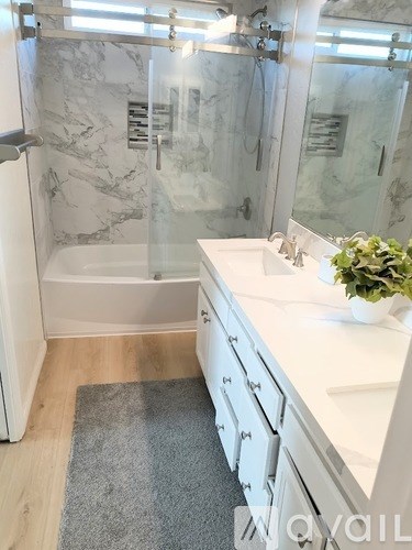 A bathroom with a marble shower and a white sink.