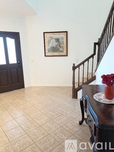 A hallway with a tiled floor and a framed picture on the wall.