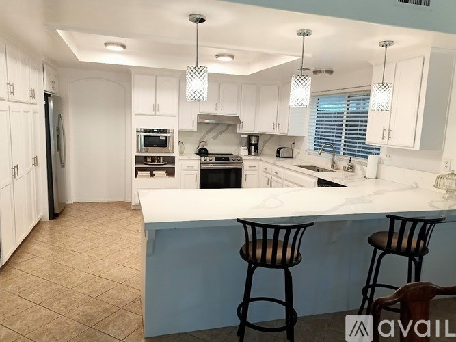 A kitchen with a white countertop and bar stools.