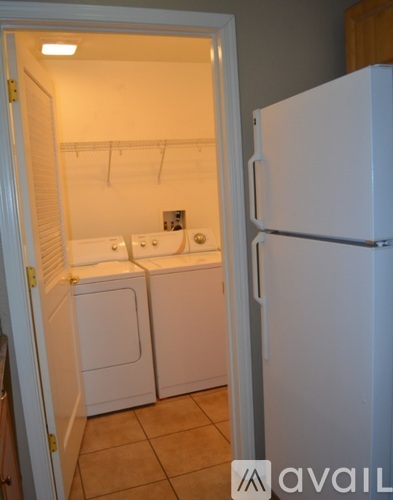 A white refrigerator stands in a kitchen with a white door and a white washing machine.