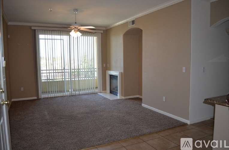 A living room with a carpet, a ceiling fan, and a fireplace.