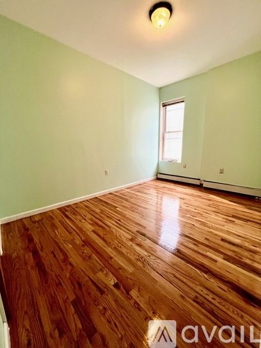 A room with wooden flooring and a window.
