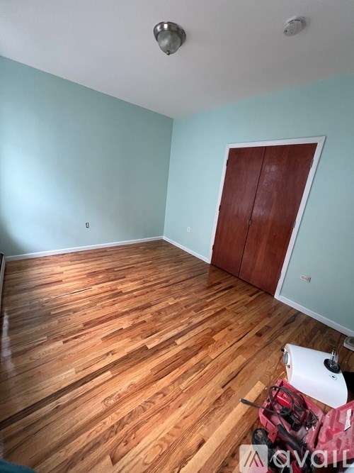 A room with wooden flooring and a closed brown door.