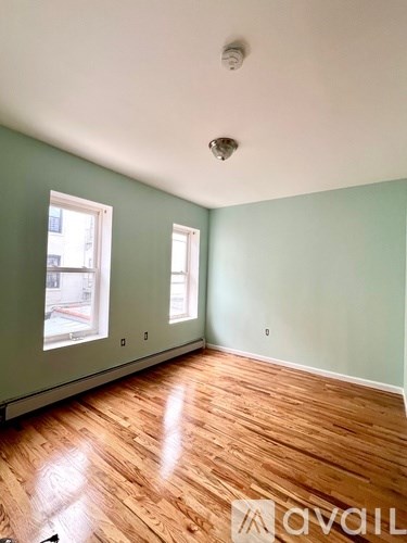 A room with wooden floors and two windows.