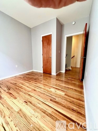A room with wooden flooring and two doors.
