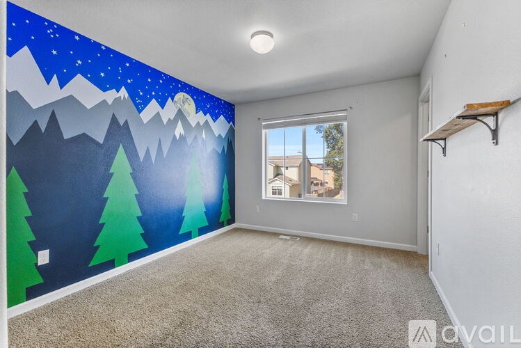 A room with a wall mural of a mountain landscape and a window showing an outdoor view.