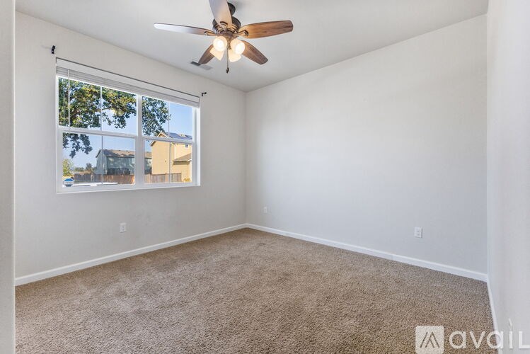 A room with a ceiling fan and carpeted floor.