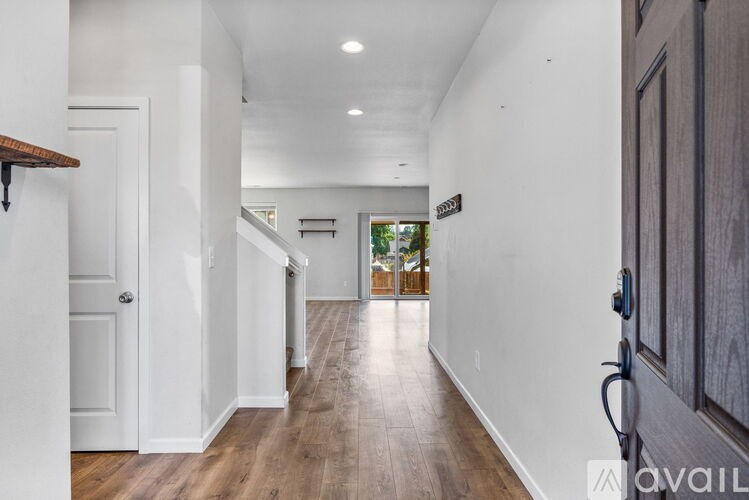 A long hallway with a wooden floor and white walls.