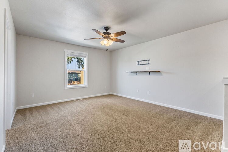 A room with a ceiling fan and a window with a view of a cityscape.