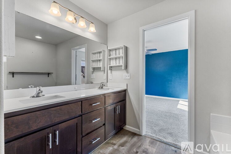 A bathroom with a large mirror, two sinks, and wooden cabinets.