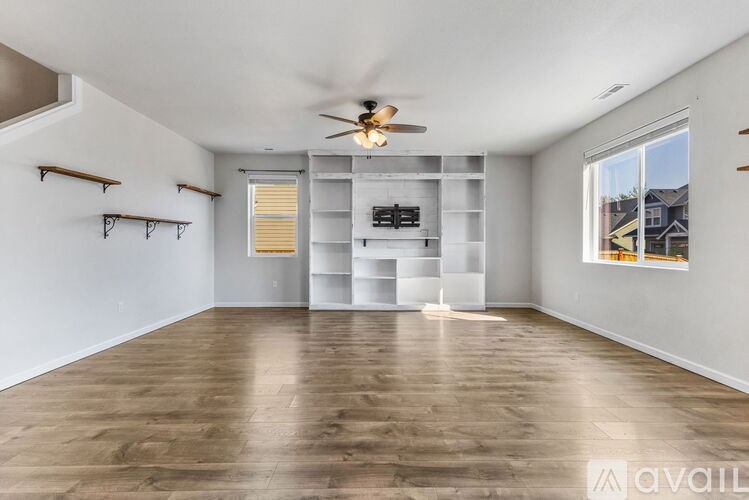 A spacious room with a ceiling fan and built-in shelves.