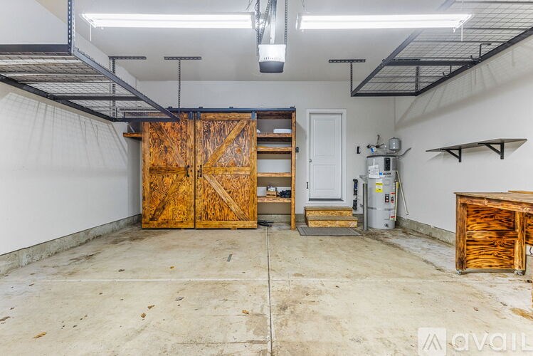 A large wooden door in a room with a concrete floor and white walls.