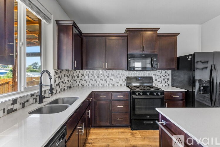 A kitchen with dark brown cabinets and black appliances.