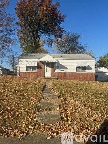 A house with a white roof and a tree with orange leaves in front.