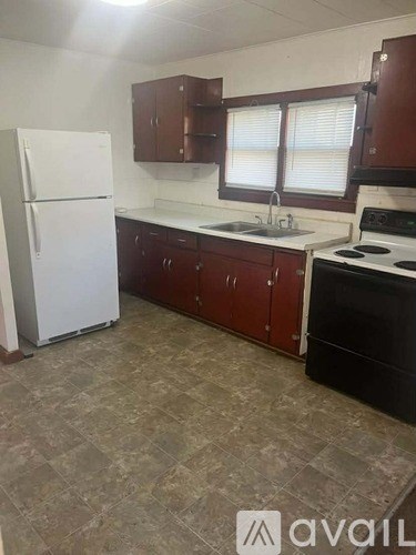 A kitchen with a white fridge, brown cabinets, and a black stove.