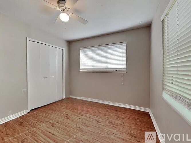 A room with a ceiling fan and a window with blinds.