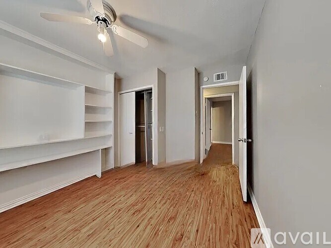 A room with a ceiling fan and wooden flooring.
