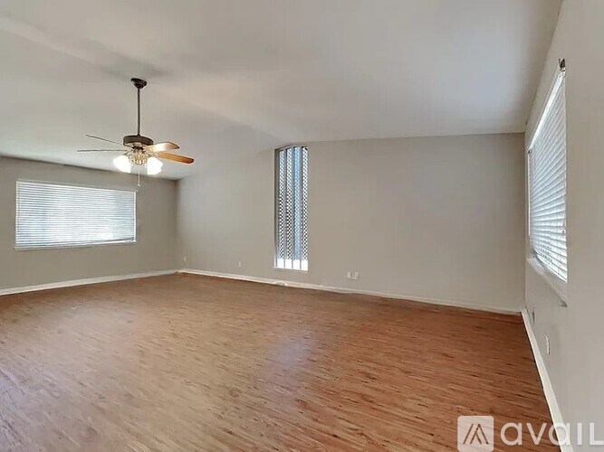 A room with wooden flooring and a ceiling fan.