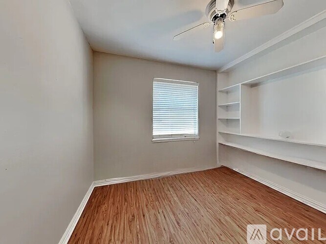 A room with a ceiling fan and a window with blinds.