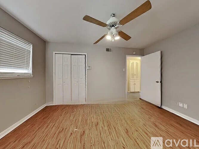 A room with a ceiling fan and wooden flooring.