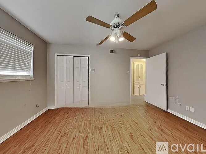 A room with a ceiling fan and wooden flooring.