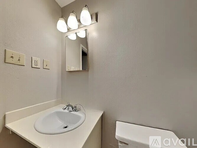 A white sink is under a mirror in a bathroom.