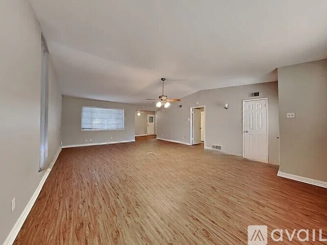 A spacious room with wooden flooring and a ceiling fan.