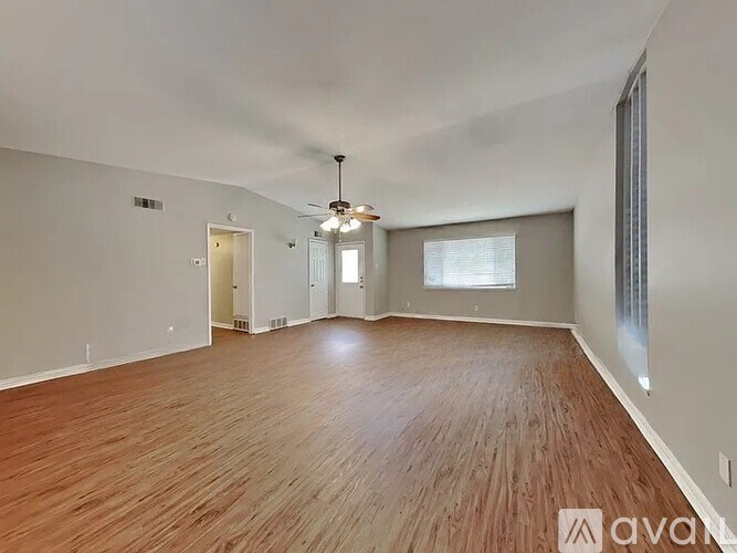 A spacious room with wooden flooring and a ceiling fan.