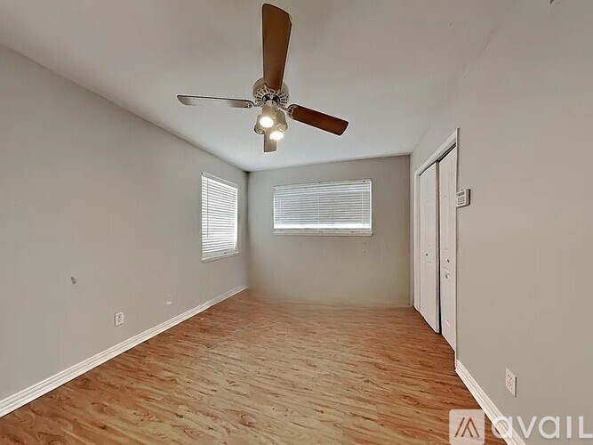A room with a ceiling fan and wooden flooring.