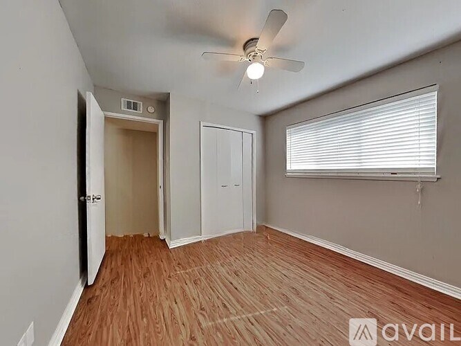 A room with a ceiling fan and wooden flooring.