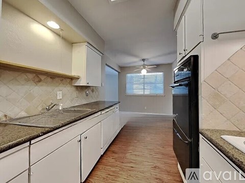 A kitchen with white cabinets and a black refrigerator.