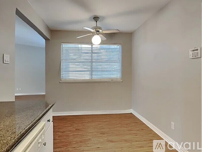 A room with a ceiling fan and a window with blinds.