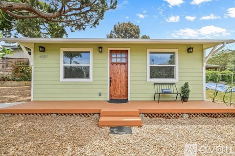 A small house with a brown door and a brown bench in front.