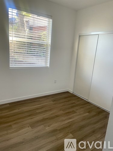 A room with a window covered by blinds and a wooden floor.