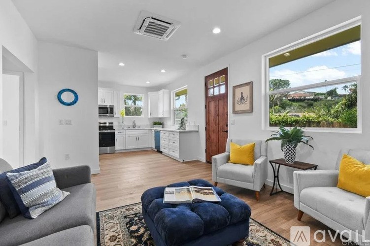 A living room with a grey couch, a blue ottoman, and a white wall with a circular blue decoration.